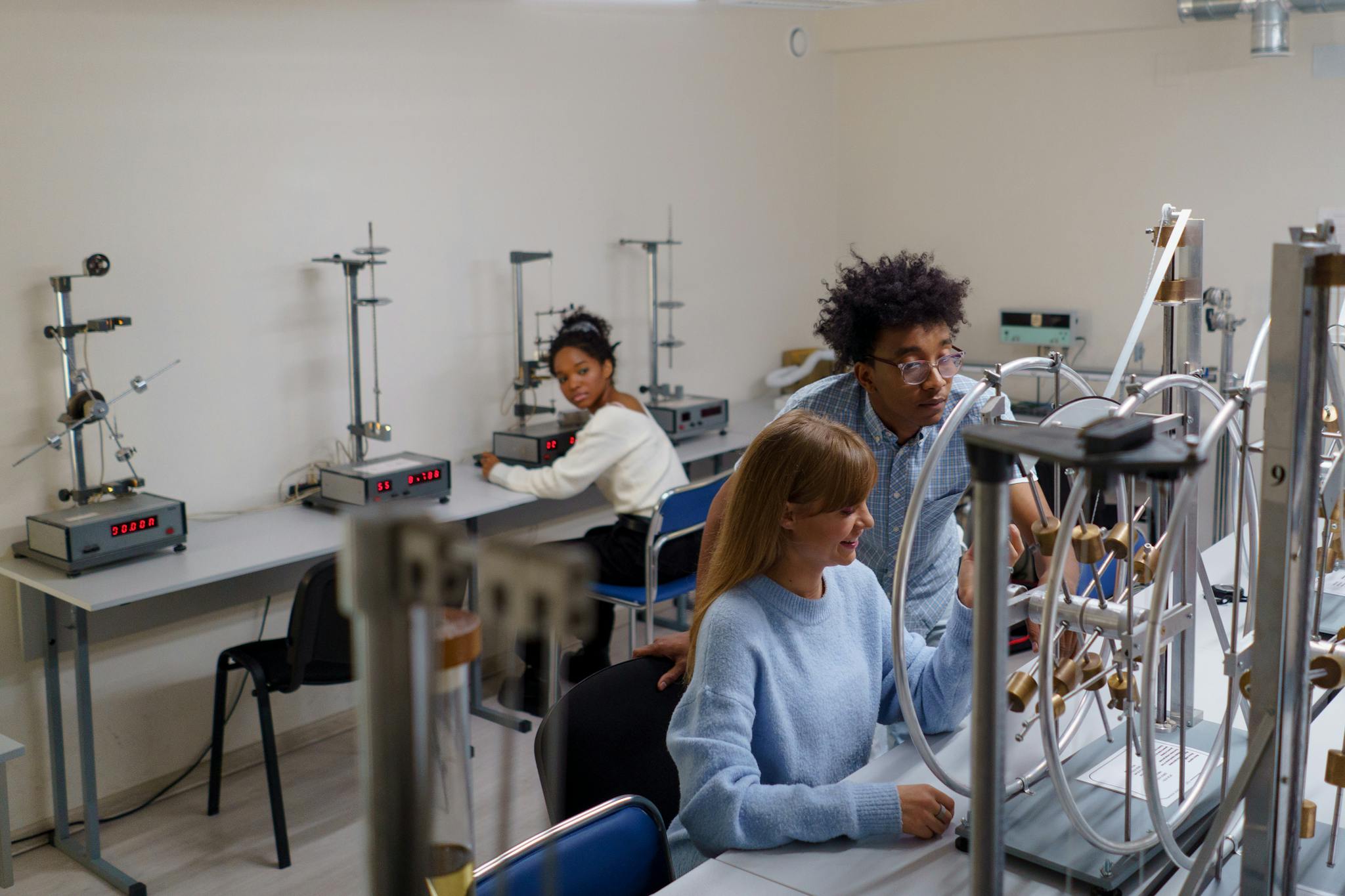 University students conducting physics experiments in a science laboratory, collaborating and learning in an interactive setting.